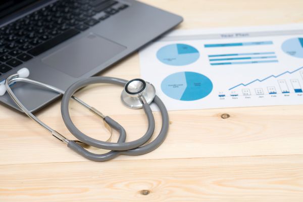 Healthcare cost accounting Laptop with stethoscope and financial reports on a doctor's desk
